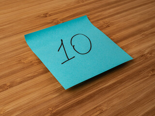 A paper sticker pasted on a wooden surface with the image of the number ten