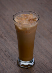 a glass of iced Thai tea on a wooden table