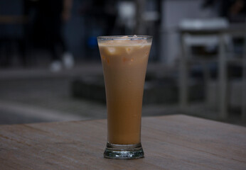a glass of iced Thai tea on a wooden table