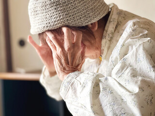 頭が痛い高齢女性の手