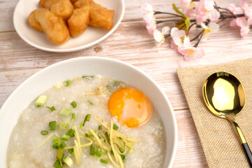 Hot Chinese Pork Congee or Chinese Rice Porridge topped with soft boiled egg, fresh ginger and coriander, served with deep fried dough stick, good for breakfast or light meal.