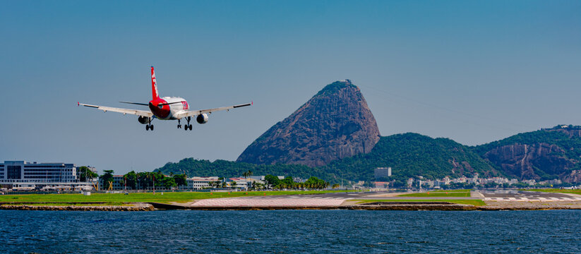 Rio de Janeiro, Brazil - December, 2020: Commercial plane landing on the runway at Santos Dumont national airport. It is possible to see the Guanabara Bay and Sugarloaf Mountain, Rio's tourist attract
