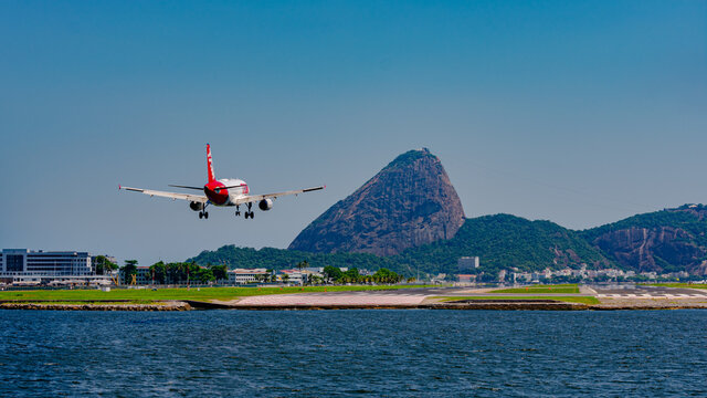 Rio de Janeiro, Brazil - December, 2020: Commercial plane landing on the runway at Santos Dumont national airport. It is possible to see the Guanabara Bay and Sugarloaf Mountain, Rio's tourist attract