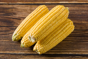 fresh raw corn cobs on wooden table