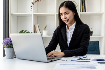 Fototapeta premium Businesswoman viewing financial data on laptop, she is reviewing financial data to bring to meetings with business partners. Concept of company financial management. Checking financial information.