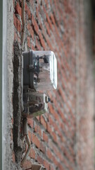 An electricity meter mounted on the wall of the house