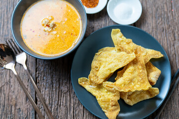 Fried wontons stuffing with minced pork, easy recipe, snacks, served with special sweet sauce on wooden vintage table