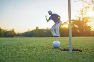 Poster Golfer action to win after long putting golf ball on the green golf, lens flare on sun set evening time. © somchai