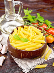 Penne in bowl of coconut with vegetables on dark board