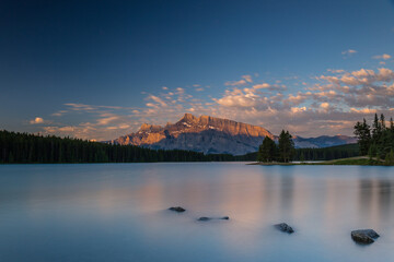 Rundle Mountain reflecting in Two Jack Lake in Banff National Park at sunrise.