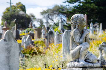 Boy statue sitting and praying at Cemetery .
