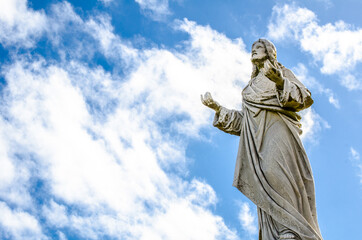 Fototapeta premium Jesus Christ statue standing against the cloudy sky day.
