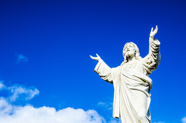 Jesus Christ statue standing against the blue sky.