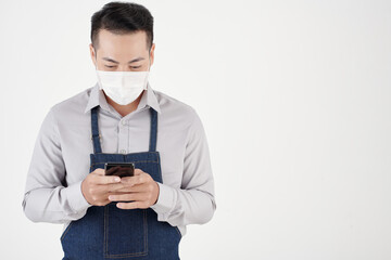 Coffeshop waiter in protective mask checking online orders from customers on smartphone