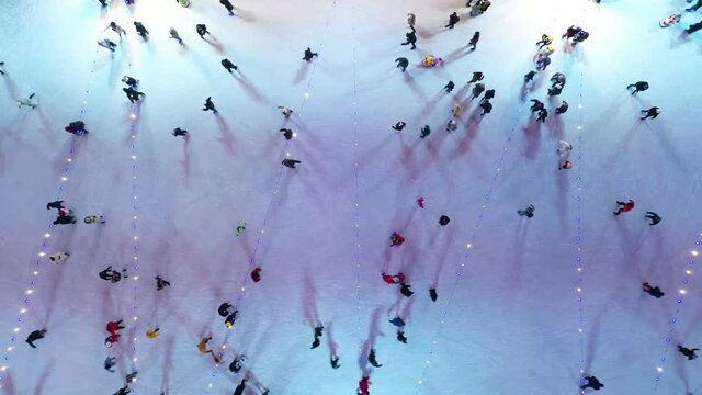 People skating on the Winter  ice rink. Ice skaters on the City Park Ice Rink at Christmas time shot from above. overhead aerial shot of many people skating in wide outdoors ice rink. 