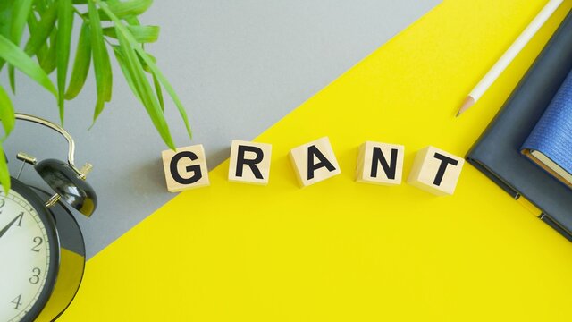 GRANT Text Written On Wooden Cubes With Pencil, Decorative Plant,alarm Clock And Notepad . Business Concept