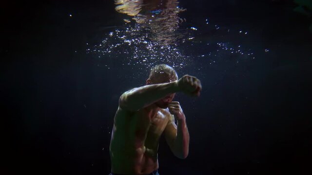 aggressive furious man with muscular naked torso is floating underwater, fighting with enemy