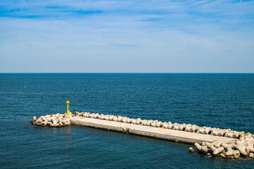 Obraz premium Coast breakwaters protecting from large waves with sea water background.