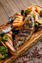 Closeup on assorted grilled fish set on wooden serving board