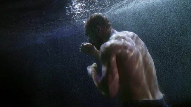 fighter underwater, man is boxing and swimming inside sea or lake, subaquatic shot
