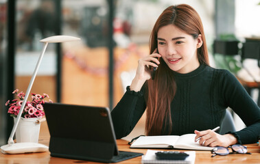 Portrait of beautiful smiling young entrepreneur businesswoman using mobile phone and working in modern work station.