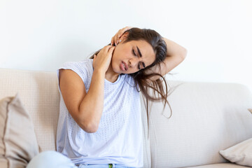 Young woman suffering from neckpain. People, healthcare and problem concept - unhappy woman suffering from neckpain at home. Neckpain caused by not taking care of health.