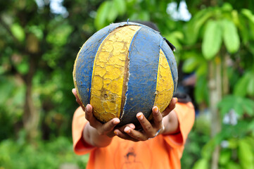 An unidentified girl is holding a volleyball that has broken its surface
