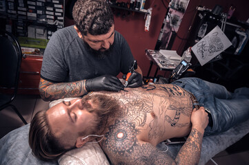 Professional tattooer demonstrates the process of getting tattoo in tattoo studio