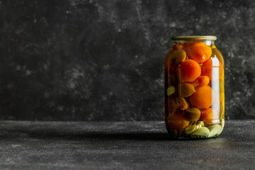 pickled tomatoes in glass on a dark background with copy space