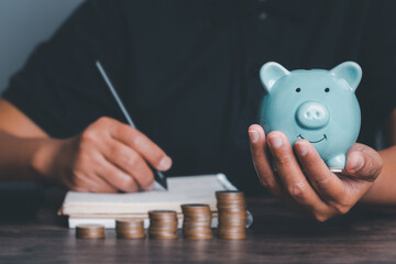 Woman hand holding piggy bank on wood table, saving money wealth and financial concept, Business, finance, investment, Financial planning,vintage picture style concept.