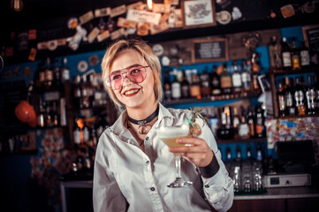 Charming woman mixologist is pouring a drink