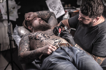 Tattoo master makes tattoo in tattoo studio