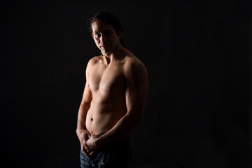 Fototapeta premium low key portrait of a man with tattoo looking at camera on black background