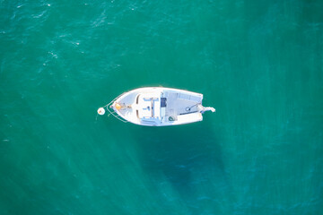 Empty fishing boat from high in atlantic. Aerial view of small white ship on green sea water....