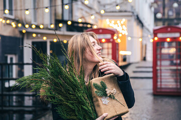 Young woman with a Christmas tree and a gift box on a blurred background.