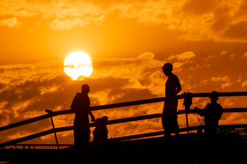 Silhouettes of construction workers on the background of the sunset sky with a huge disk of the sun