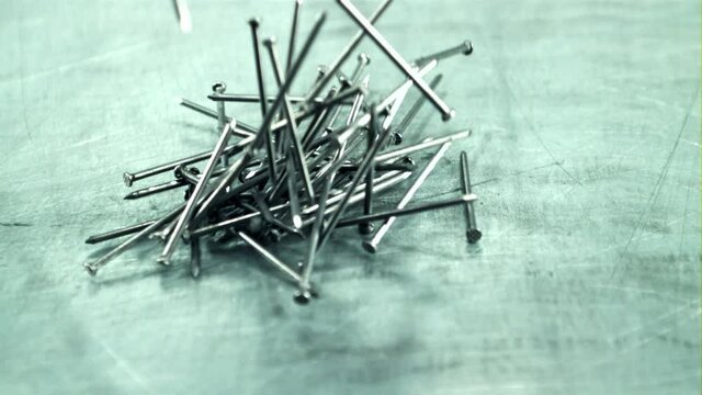 A bunch of nails fall on the table. On a gray background. Filmed is slow motion 1000 fps.