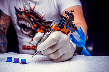 Hand of a tattooer and a tattoo gun.