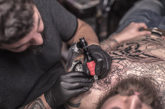 Tattooer demonstrates process of making a tattoo