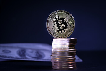  bitcoin coin stands on a stack of other gold coins