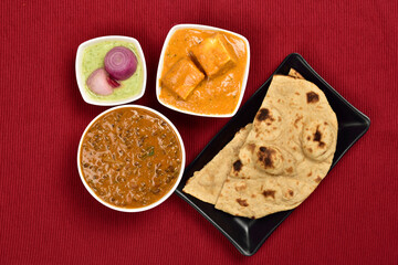 Paneer Butter Masala and Dal Makhani With Tandoori Roti and Pudina Chutney on Red Placemat