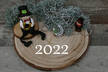 Zwei Schornsteinfeger und  Hufeisen mit der Zahl 2022  auf einer Baumscheibe.