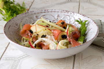 bowl of salad with fennel, celery and salmon on the table