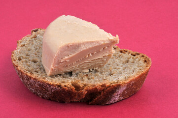 Morceau de foie gras sur une tartine de pain en gros plan sur fond rouge