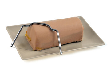 Bloc de foie gras avec une lyre à foie gras dans un plat sur fond blanc