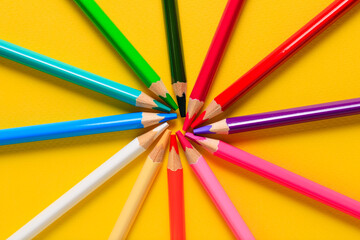 Naklejka premium Multicolored pencils on a yellow background. Wooden color pencils, colored pencils for drawing.