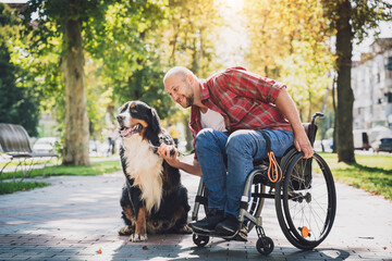 Happy young man with a physical disability who uses wheelchair with his dog.