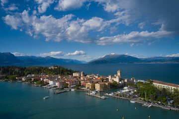 Naklejka na ściany i meble Sirmione, Lake Garda, Italy. Aerial view of the island of Sirmione. Castle on the water in Italy. Panorama of Lake Garda. Peninsula on a mountain lake in the background of the alps.