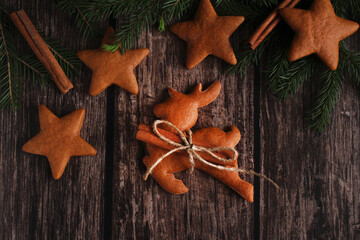 ginger biscuits in the form of deer and stars on a wooden background with spruce branches
