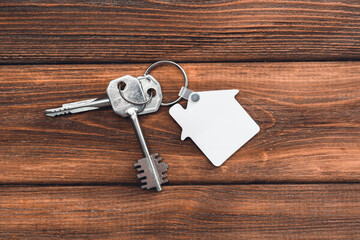 Keychain house shaped mockup on rustic wooden background. Blank white sublimation keychain.